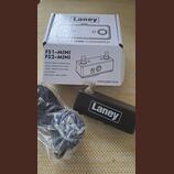 Na fotografii je černý nožní spínač značky Laney a jeho originální kartónové balení. Krabice nese nápisy Laney, FS1/FS2-MINI FOOTSWITCH a technické s…