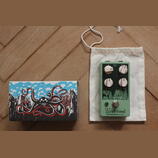 Zelený efekt pedál s nápisy Level, Drive, Bass a Treble u ovládacích knoflíků. Ve spodní části je logo Westwood a text EarthQuakerDevices. Vedle pedá…