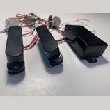 Tři černé elektrické snímače kytary s plastovými kryty. V pozadí jsou vidět zapojené potenciometry a elektrické součástky s červenými, bílými a zelen…