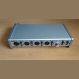 Stříbrný audio interface s kovovým šasi. Na předním panelu je nápis TASCAM a model SERIES 208i. Zařízení obsahuje čtyři vstupní kanály s konektory, o…