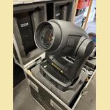Černý movable head reflektor umístěný v transportním kufru s pěnovou výplní. Zařízení má matný plastový povrch a velkou přední čočku. Na boku jsou vi…