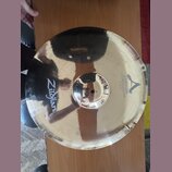 Zlatavý kovový činel s vyznačeným okrajem. Na povrchu je černý nápis Zildjian a logo A s textem CUSTOM 20th Anniversary Ride MEDIUM Thin 22". Povrch…