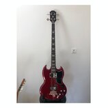 Čtyřstrunná basová kytara s červeným lesklým povrchem těla a černou hlavou. Na hlavě je nápis Epiphone. Tělo má charakteristický SG tvar, černý pickg…