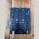 Černý DJ mixér s nápisem Pioneer DJ a označením modelu 2 CHANNEL DJ MIXER DJM-450 v pravém dolním rohu. Zařízení obsahuje zahlreiche potenciometry, p…