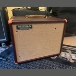 Kytarový kombo zesilovač v hnědém vinylovém potahu s koženou rukojetí a rohovými chrániči. Přední mřížka je v béžové barvě a nese stříbrno-černý ovál…
