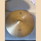 Zlatavý kovový činel s viditelným kovaným povrchem. Na horní části je černý nápis K.ZILDJIAN a pod ním menší text CONSTANTINO PLEI spolu s logem. Ve…