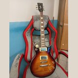 Elektrická kytara typu Les Paul s barevným přechodem od žluté k tmavě hnědé. Na hlavě hmatníku je bílý nápis Harley Benton. Nástroj má dva humbuckery…