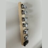Fotografie zachycuje dřevěný hmatník s šestnácti stříbrnými ladicími mechanismy. Dřevo má světlou barvu a je v nebarveném stavně. Na spodní části je…