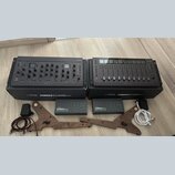 Dvě šedé studiové kontroléry Softube, model CONSOLE 1 CHANNEL Mk III a CONSOLE 1 FADER Mk III. Pod nimi jsou dvě krabice s nápisy Softube CONSOLE 1 C…