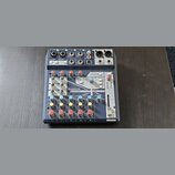 Mixážní pult Soundcraft NOTEPAD-BFX v tmavě šedé barvě s kovovými prvky. Na předním panelu jsou vidět různé vstupy, potenciometry a červené tlačítka.…