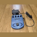 Modrá kytarová stupňová pedál s nápisem GUITAR GDI 21 a logem behringer. Zařízení má čtyři ovládací knoflíky s popisky DRIVE, TREBLE, BASS a LEVEL, n…