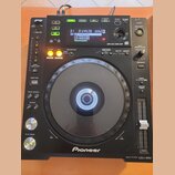 Černý digitální DJ player značky Pioneer, model CDJ-850 MULTI PLAYER. Zařízení má velký kruhový jog wheel, fader tempo a řadu ovládacích tlačítek s n…