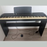 Černý digitální piano s klaviaturou a integrovaným stojanem. Na horní části je nápis KORG a nad klávesami je umístěna černá hudební stránkovka. Nástr…