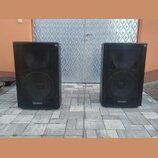 Dva černé reproduktorové boxy s kovovými mřížkami přes celé přední strany. V dolní části obou boxů je bílý nápis Voice Master. Povrch krytů vykazuje…