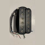 Černý humbucker s dvěma řadami šesti viditelných pólů. Nástroj má plastový kryt a připojovací kabely v červené, bílé, zelené a černé barvě. Povrch pl…