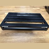 Černý kovový pedalboard s mřížkovou konstrukcí a protiskluzovými gumovými pásky. Na přední hraně je bílý nápis pedaltrain a v pravém dolním rohu ozna…