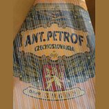 Detailní pohled na dřevěný nástroj s napnutými strunami. Na povrchu je vidět dekorativní nápis ANT. PETROF a pod ním text CZECHOSLOVAKIA. Ve spodní č…