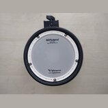 Kruhová elektronická bubenová plocha s bílým síťovým povrchem a černým vnějším rámem. Na ploše jsou nápisy „Roland“, „MESH HEAD“, „Reg. U.S. Pat. & T…