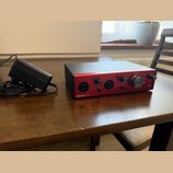 Černý audio rozhraní s červeným předním panelem a nápisem Clarett+ 2Pre. Na horní straně je bílý nápis Focusrite. Zařízení má několik ovládacích knof…