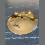 Zlatavý kovový činel s centrálním otvorem. Na povrchu je černý nápis CLASSICS — CUSTOM — 8" Bell. Povrch je hladký a vykazuje odrazy okolí.