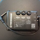 Černý efektový pedál s nápisem TONEWOODAMP. Na horní straně jsou tři černé ovládací knoflíky a tabulka s popisy funkcí Effects, Parameters a Amplitud…