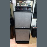 Kytarový stack tvořený černou zesilovací hlavou a dvěma reproduktorovými boxy. Na hlavě je nápis CARVIN RT-120 a RED LINE, na spodní části obou boxů…