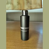 Černý kovový válcový objekt s kovovým konektorem v horní části. Na boku je bílý nápis KLARKTEKNI a pod ním text MIC BOOSTER CT. Povrch je matný a v d…