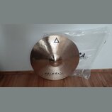 Kruhový mosazný činel s viditelným broušením povrchu. Na horní části je černý trojúhelník a nápis XIST, ve spodní části nápisy istanbul Agop Made in…