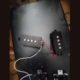 Dvě černé elektrické snímače s čtyřmi viditelnými kovovými póly, položené na černém povrchu. Snímače jsou propojeny červenými a bílo-černými vodiči.…