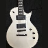 Bílá elektrická kytara s tvarem připomínajícím Les Paul a bílým lemováním kolem korpusu. Nástroj je vybaven dvěma černými humbuckery s oranžovým nápi…