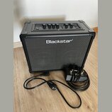 Černý kytarový kombo zesilovač s nápisem Blackstar na přední textilní mřížce. Horní ovládací panel obsahuje několik otočných potenciometrů a přepínač…