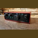 Červený audio rozhraní s černým předním panelem. Na panelu jsou nápisy Output, Direct a Scarlett Solo, čtyři otočné ovladače a několik malých zelenýc…