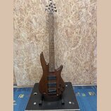 Elektrická basová kytara s tmavě hnědým dřevěným povrchem a čtyřstrunnovým hmatníkem. Na hlavě je vidět bílý nápis "YAMAHA". Nástroj má dva černá sní…