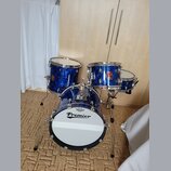 Modrá bicí souprava s marbled povrchem, která obsahuje basový rám, dva tom-tomy a jeden snare drum. Na basovém rÁmu je bílá blana s nápisy REMO a Pre…