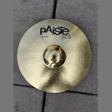 Zlatý mosazný činel typu hi-hat s koncentrickým žebrováním povrchu. Na povrchu je černý nápis pAiste, označení 101 BRASS a text 14" HI-HAT TOP. Povrc…