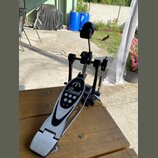 Černý basový pedál s kovovým šlapadlem v stříbrné barvě. Na šlapadle je umístěno logo Pearl a čtyři bílé tečky. Pedál vykazuje mírné známky používání…