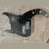 Černý plastový pickguard pro basovou kytaru s vyřezem pro snímače. Na povrchu je bílý nápis Fender PLAYER II SERIES PRECISION BASS s doplňujícími tex…