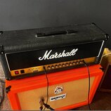 Černý kytarový kombozesilovač značky Marshall s bílým nápisem Marshall a označením JCM 900 50W HC Lead Dual Reverb. Přední panel obsahuje řadu ovláda…