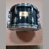 Černý buben s chromovaným obručováním a ladidly. Na korpusu je zlatý štítek s nápisy Pearl, MAPLE SHELL, 000170 a MADE IN JAPAN. Povrch nástroje je g…