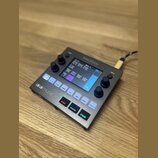 Kompaktní černý sampler s displejem a ovládacími prvky. Na horní hraně je nápis blackbox, v levém dolním rohu logo 1010music. Zařízení obsahuje někol…