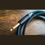 Černý audio kabel s pleteným oplatením a pozlaceným 6,3mm jack konektorem. Na černém plastovém krytu konektoru je vyražen nápis NEUTRIK. Povrch kabel…