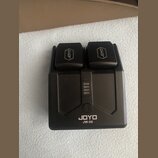Černá nabíječka na baterie s dvěma sloty. Na horních krytech je logo JOYO a v dolní části nápis JOYO JW-06. Uprostřed se nachází kontrolka s čtyřmi s…