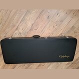 Černý tvrdý kufýr na hudební nástroj s rukojetí a kovovými zapínacími prvky. V pravém dolním rohu je zlatý nápis Epiphone. Povrch kufýru vykazuje dro…