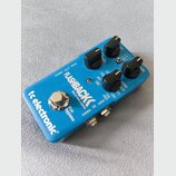 Modrý efekt pedál s nápisy FLASHBACK DELAY AND LOOPER a tc electronic. Na horní straně jsou čtyři černé oválné ovládací knoflíky a přepínače s popisk…