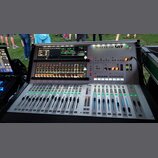Stříbrný digitální mixážní pult s dvěma vestavěnými displeji. V pravém horním rohu je nápis Soundcraft Vi1. Zařízení obsahuje řadu posuvníků, tlačíte…