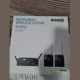 Fotografie znázorňuje krabici s bezdrátovým systémem pro nástroje značky AKG by HARMAN. Na obalu je nápis INSTRUMENT WIRELESS SYSTEM a model WMS40 MI…