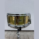 Zlatý buben s chromovanými obručemi a mechanismy, umístěný na chromovaném stojanu. Na korpusu je čtvercový štitek s nápisy Pearl, MADE IN TAIWAN a Br…