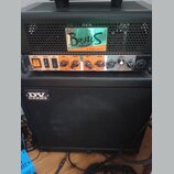 Černý kytarový kombozesilovač s logem DV MARK na přední mřížce. Horní část obsahuje ovládací panel s knoflíky Gain, Volume, Bass, Middle a Treble, př…