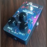 Kytarový efekt s modrým, fialovým a červeným vzorem v podobě šestiúhelníků. Na horní straně je nápis COMMANDER DISTORTION a v pravém horním rohu bílý…