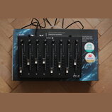 Černý MIDI kontrolér P1-X s osmi posuvníky a řadou tlačítek pod nimi. Zařízení leží na originální krabici s nápisy ICON, Extend the revolution!, BITW…